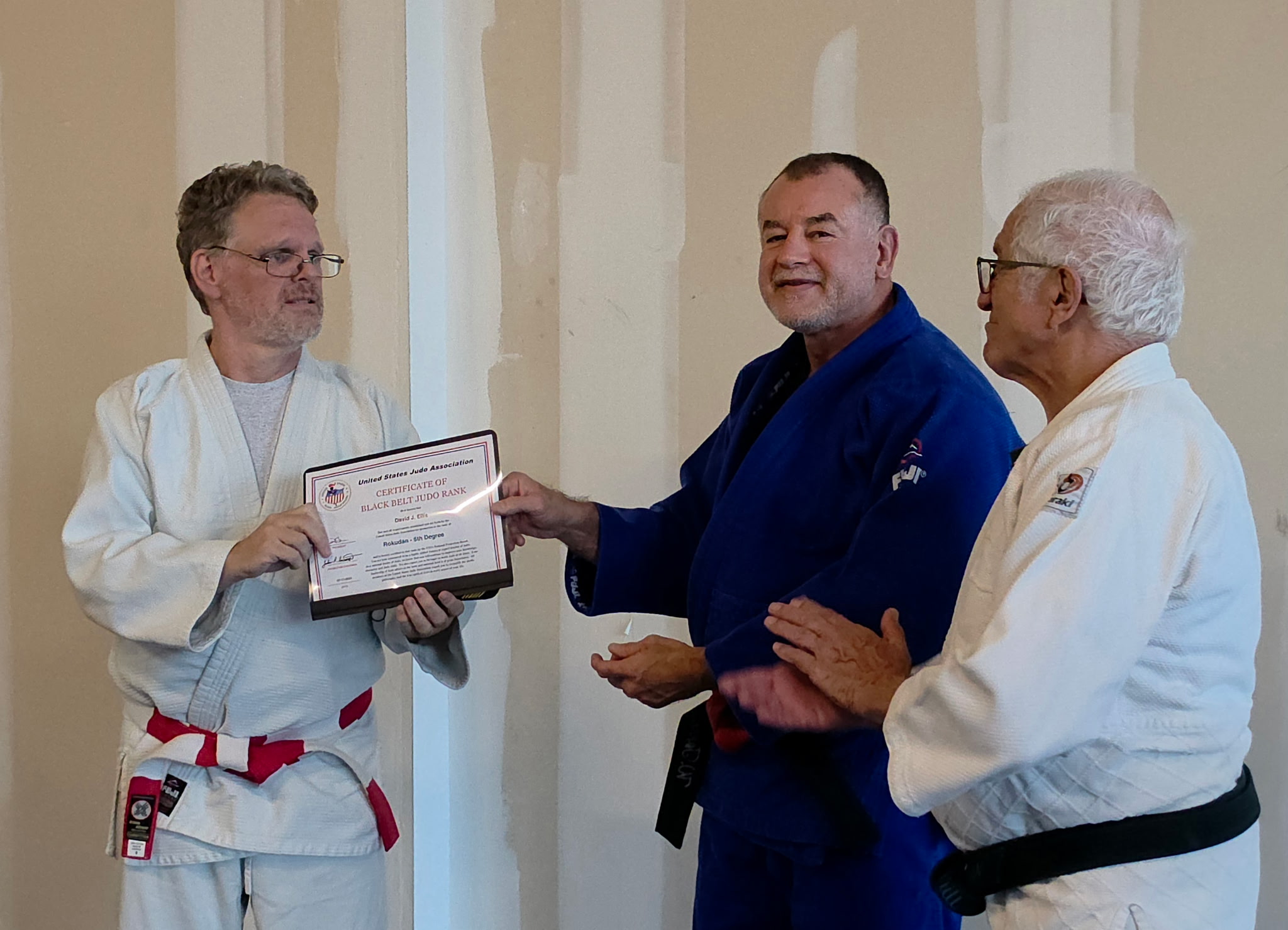 Wilfredo Torres Negron and Dr. Andre Merrill presenting David J. Ellis with his Rokudan rank certificate and a black belt key chain on July 2, 2026