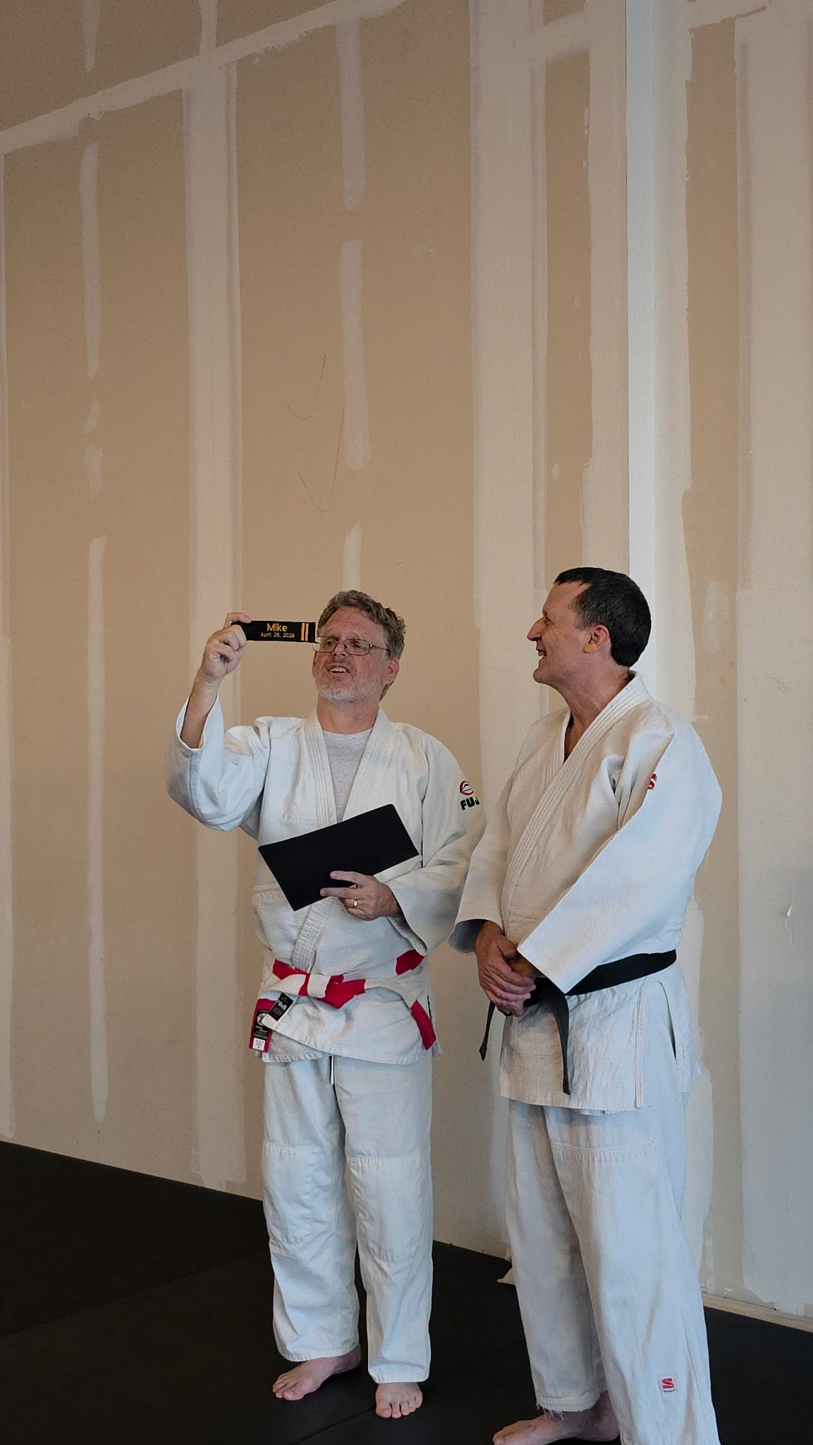 David J. Ellis presenting Mike Allison with his Nidan rank certificate and a black belt key chain on July 2, 2026