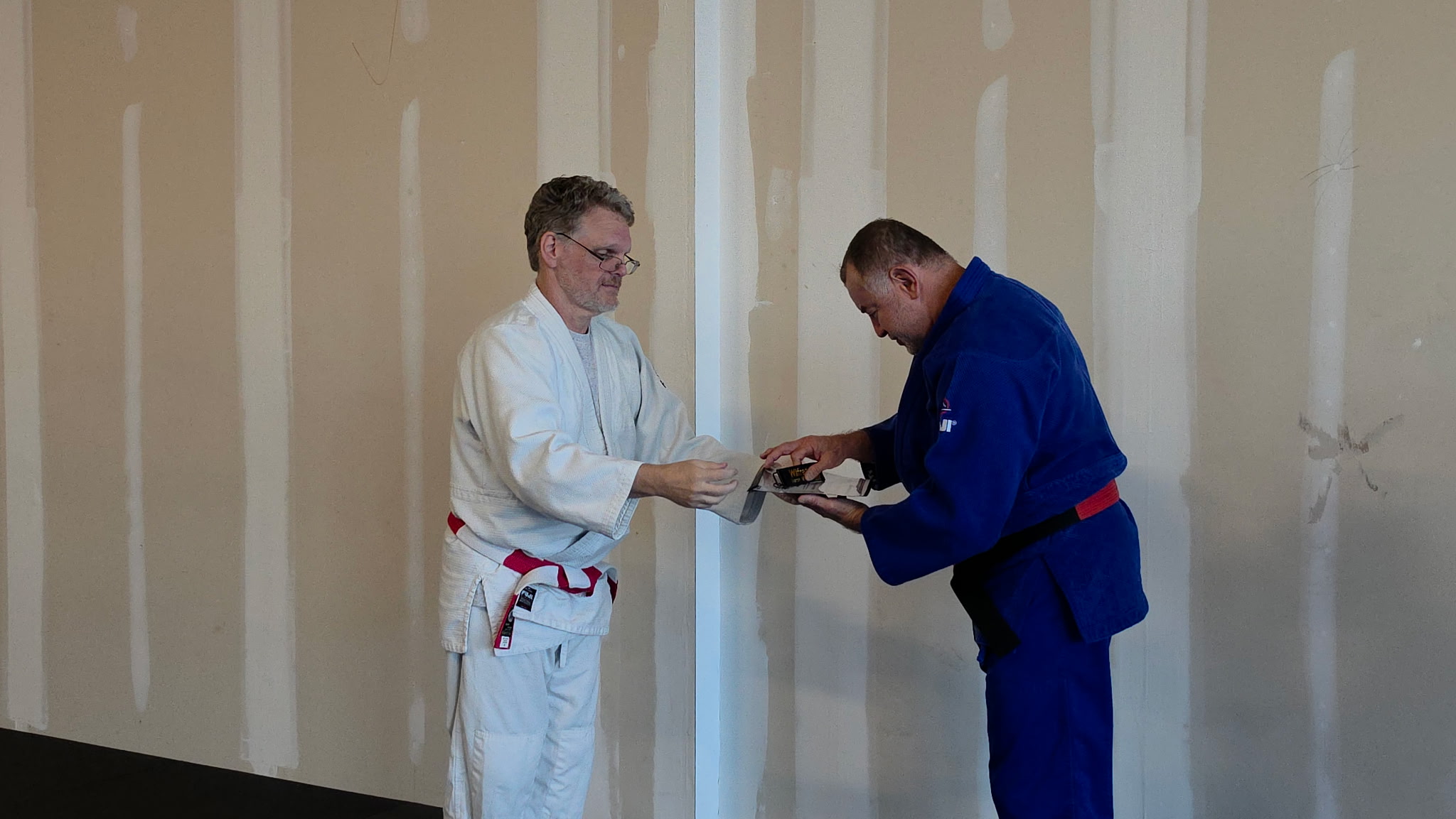 David J. Ellis presenting Wilfredo Torres Negron with his Godan rank certificate and a black belt key chain on July 2, 2026